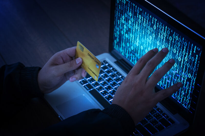 Stock photo of hands operating a laptop while holding a credit card.