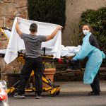 Men and women in protective gear work with a stretcher.
