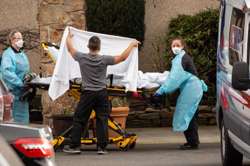 Men and women in protective gear work with a stretcher.