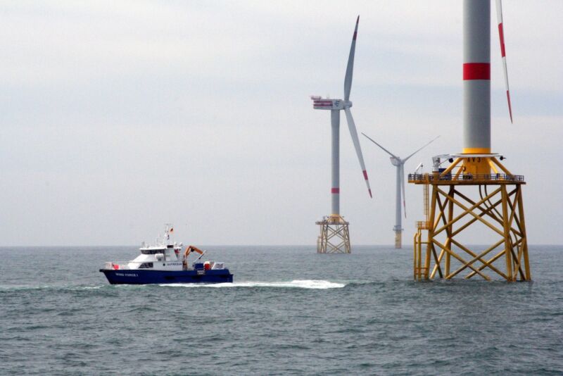 Image of a boat near the base of an offshore wind farm.
