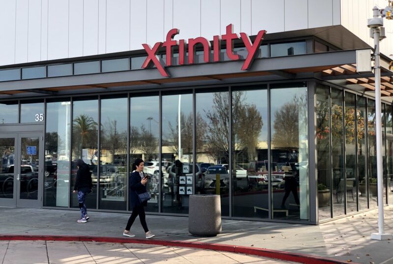 A pedestrian walking by a Comcast retail store.