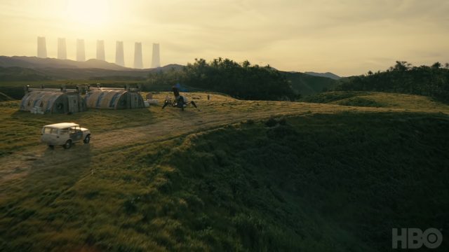 Image of a green field with some technology in the distance