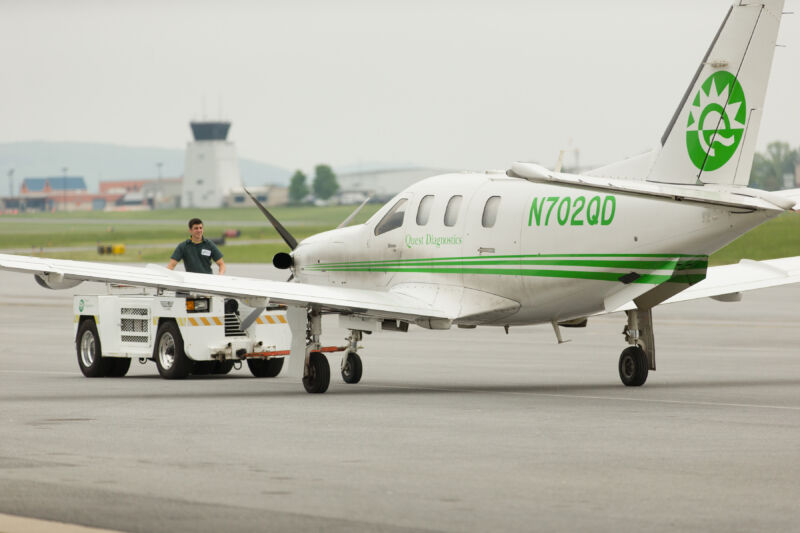 A white and green airplane belonging to Quest Diagnostics is on the ground at Reading Regional Airport