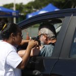 Image of a vaccine being administered to someone in a car.
