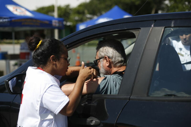 Image of a vaccine being administered to someone in a car.