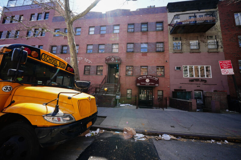 Photograph of a school bus in front of a 3-story brick building.