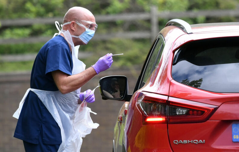 Image of a person in protective clothing standing next to a car.