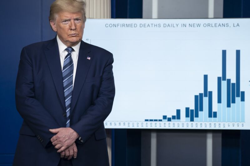 President Donald Trump at a press conference, standing in front of a chart showing the number of coronavirus deaths in New Orleans.