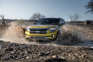 A Kia Seltos drives through a muddy puddle