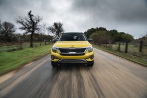 A yellow Kia Seltos drives towards the camera