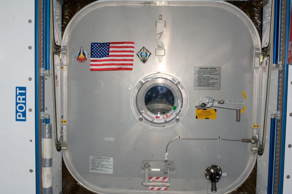 Inside the International Space Station's Node 2, the STS-135 crew presented the Expedition 28 crew this special US flag and mounted it on the hatch leading to Atlantis.