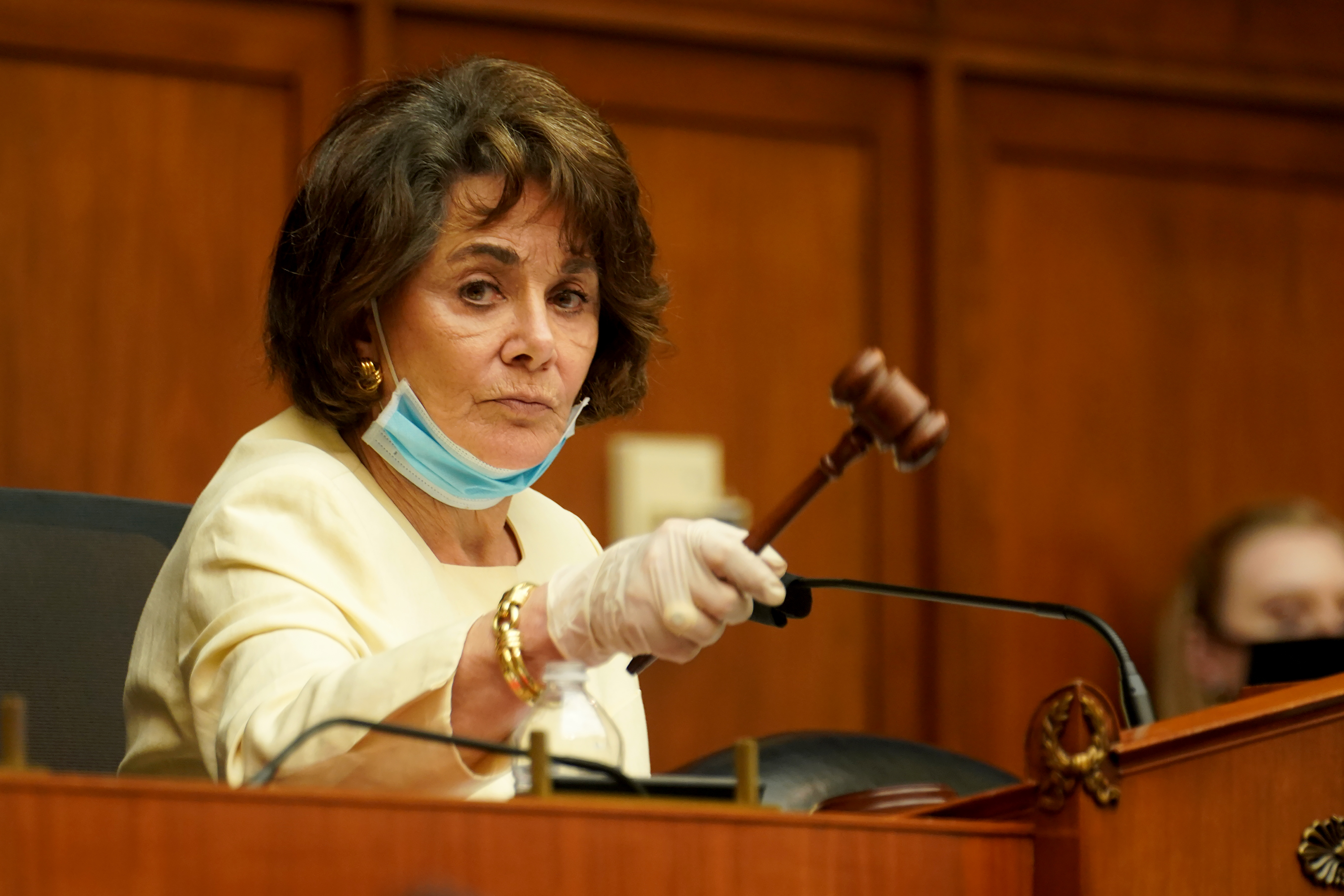 A serious woman in a suit raises a gavel.