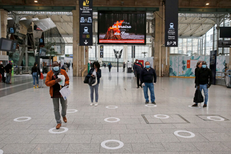 Images of people standing on a tile floor in face masks.