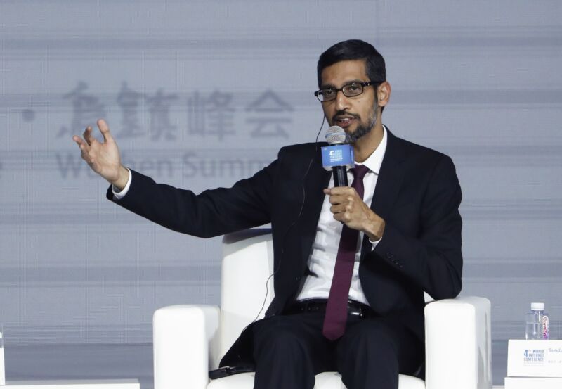 A man in a suit speaks into a microphone.