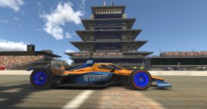 A blue and orange IndyCar drives past the Indianapolis Motor Speedway pagoda in iRacing