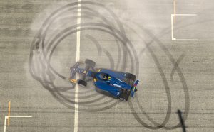 An IndyCar, viewed from above, does donuts in iRacing,