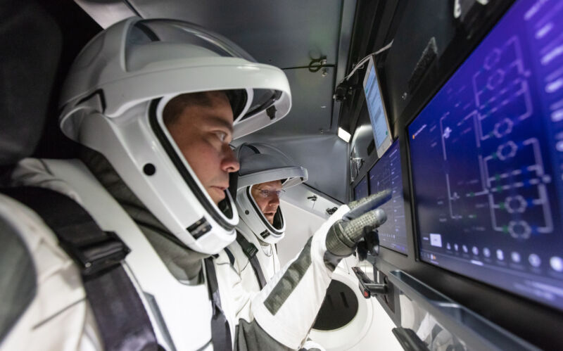 NASA astronauts Doug Hurley and Bob Behnken (foreground) enactment    connected  Crew Dragon's touchscreen displays.