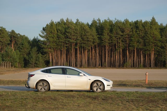 A white Tesla Model 3 outside a German forest