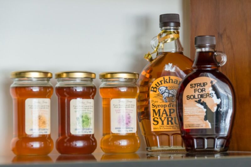 Different brands of maple syrup clutter a shelf.