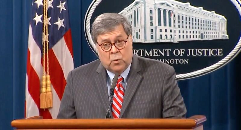 A man in a suit speaks at a podium.