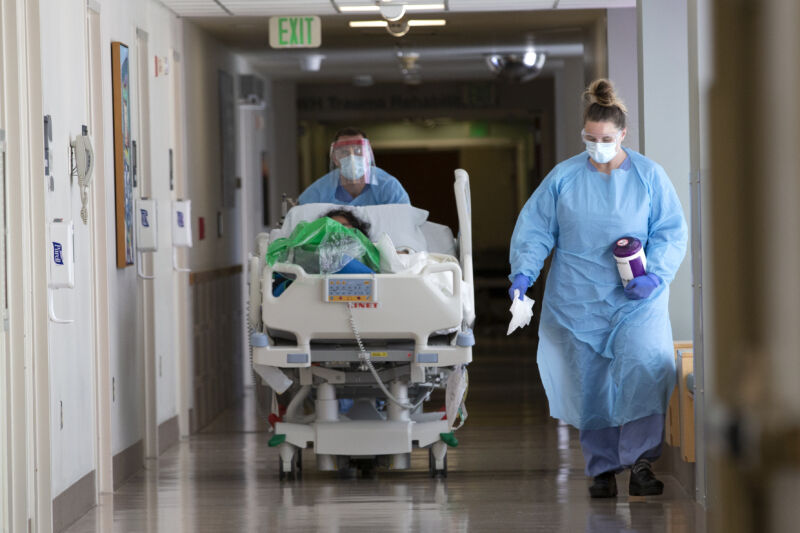 A nurse on infection control accompanies a patient being transferred from the ICU COVID unit to the acute care COVID unit at Harborview Medical Center on May 7, 2020 in Seattle, Washington. 
