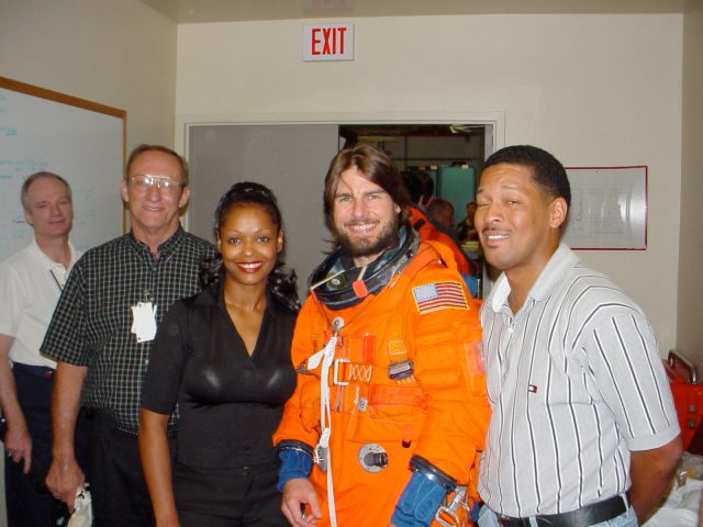 Tom Cruise wears a space shuttle-era Advanced Crew Escape Suit (ACES) pressure garment during a visit to the Jake Garn Simulator Facility at NASA’s Johnson Space Center in Houston, Texas, in September 2002. Pictured with Cruise (left to right): astronaut Charlie Precourt, Bill Todd, Sharon McDougle, and George Brittingham.