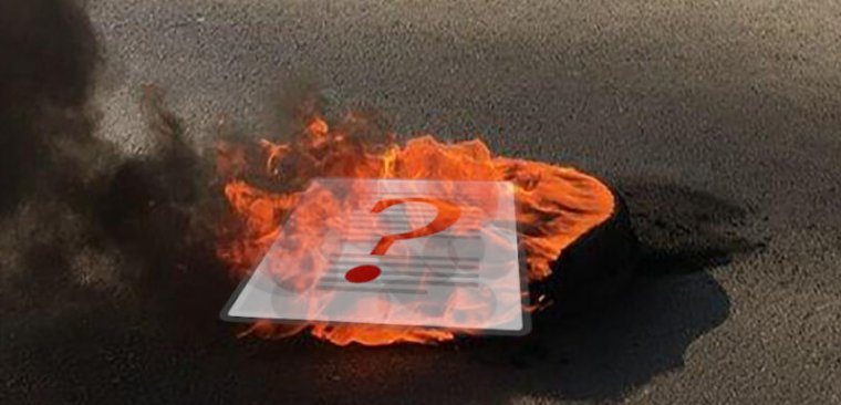 Photograph of a burning piece of paper on pavement.