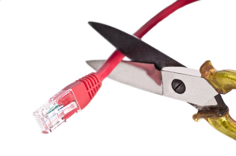 La imagen muestra unas tijeras cortando un cable Ethernet rojo, simbolizando la desconexión o interrupción del servicio de Internet.