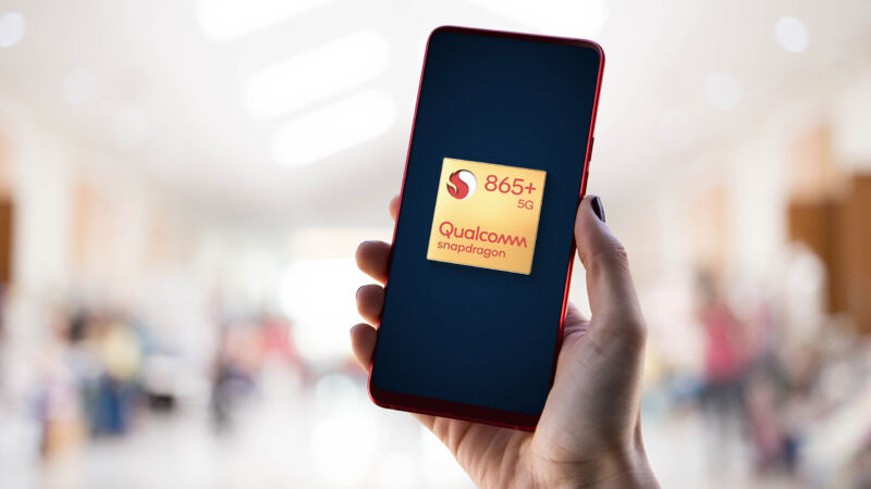 Close-up image of a hand holding a smartphone with the Qualcomm logo.
