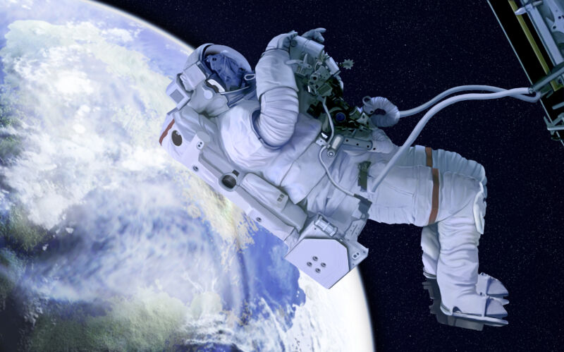 An astronaut performs a spacewalk with the Earth in the background.