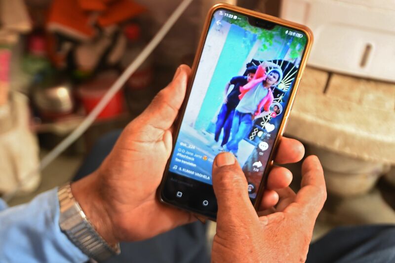 A person's hands holding a smartphone with the app TikTok displayed on the screen.