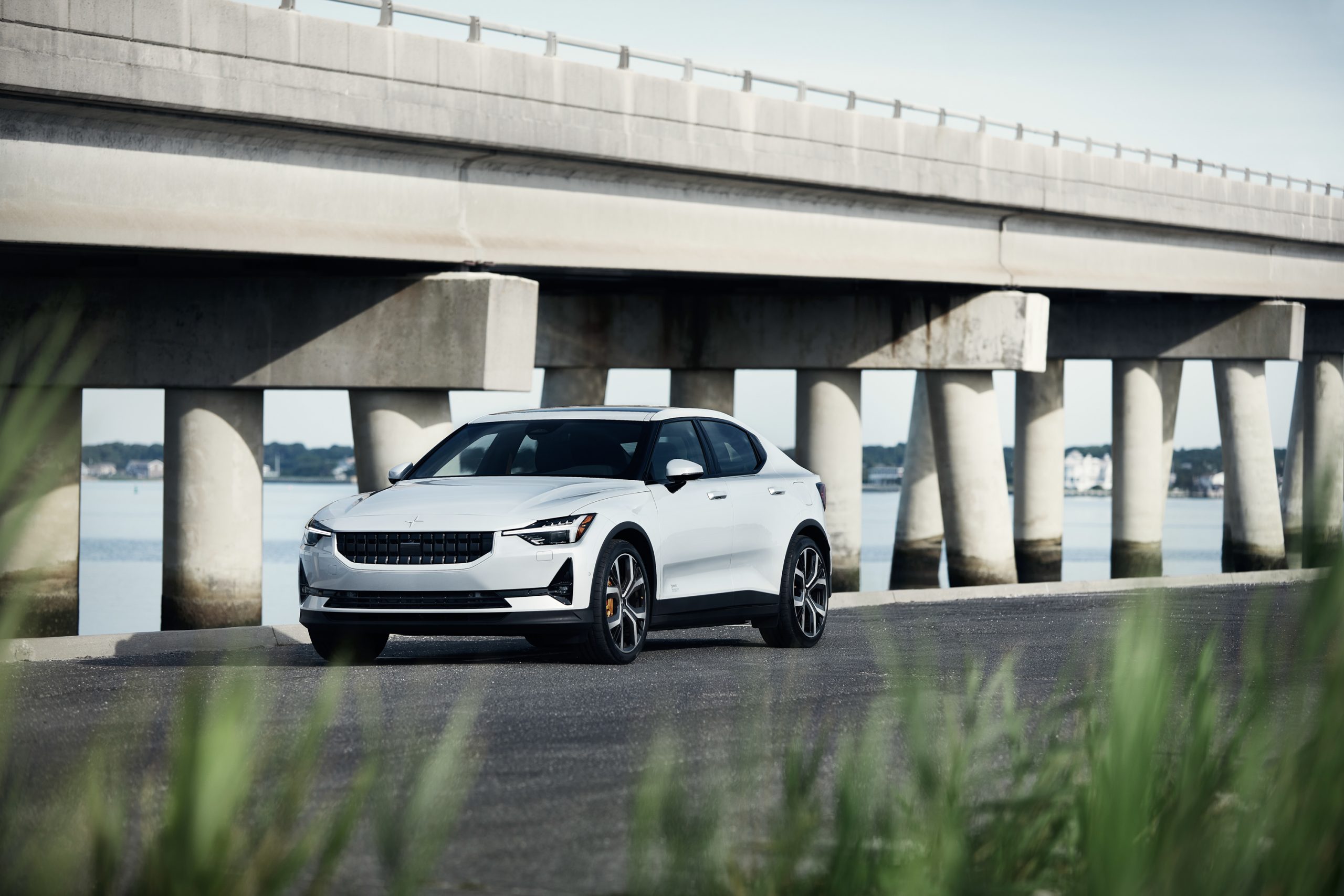 A white Polestar 2 parked next to a bridge