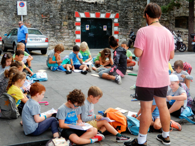 Casually dressed youngsters read forms while sitting in a parking lot.