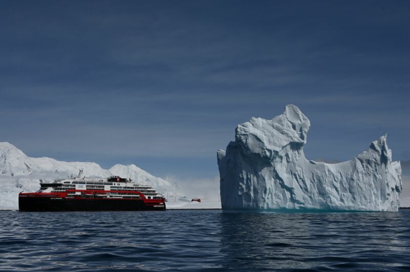 View of an iceberg and the Hurtigruten hybrid expedition cruise ship MS Roald Amundsen on Half Moon island, Antarctica on November 09, 2019. 
