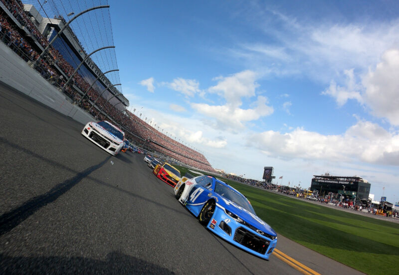 Wide-angle photo of stock cars on a race track.