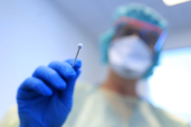 A doctor wearing personal protective equipment (PPE) prepares to take a saliva swab from a patients during coronavirus symptom tests in the coronavirus outpatient clinic at the Paracelsus Clinic in Zwickau, Germany, on Thursday, April 2, 2020. 