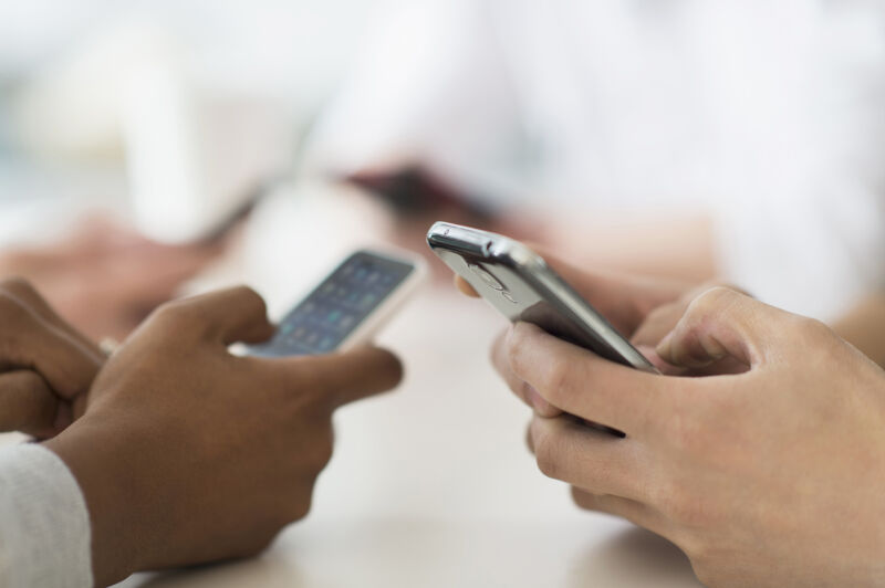 Stock photo of hands using smartphones against white background.