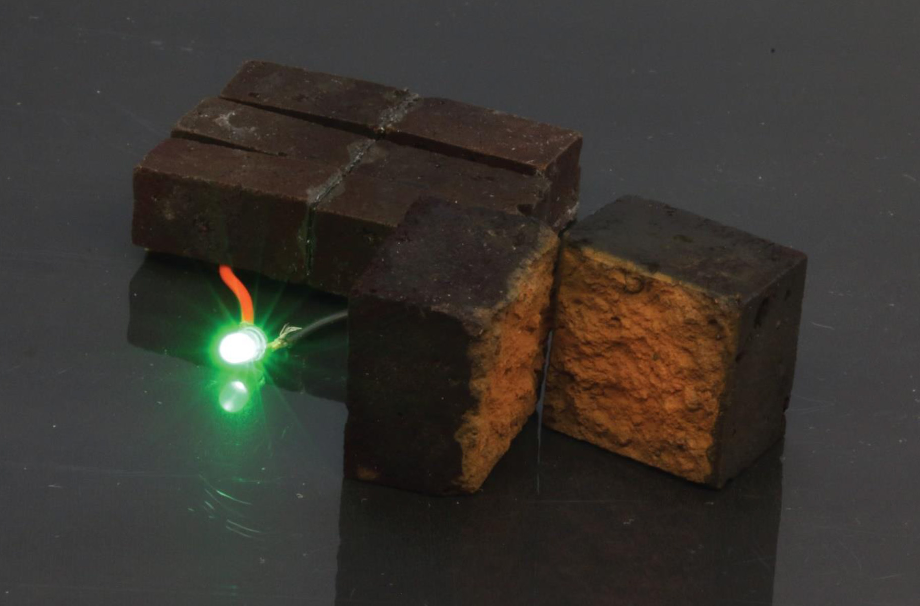 Three larger supercapacitors connected in series light up an LED. The split tile on the right shows the color change from the PEDOT overlay.