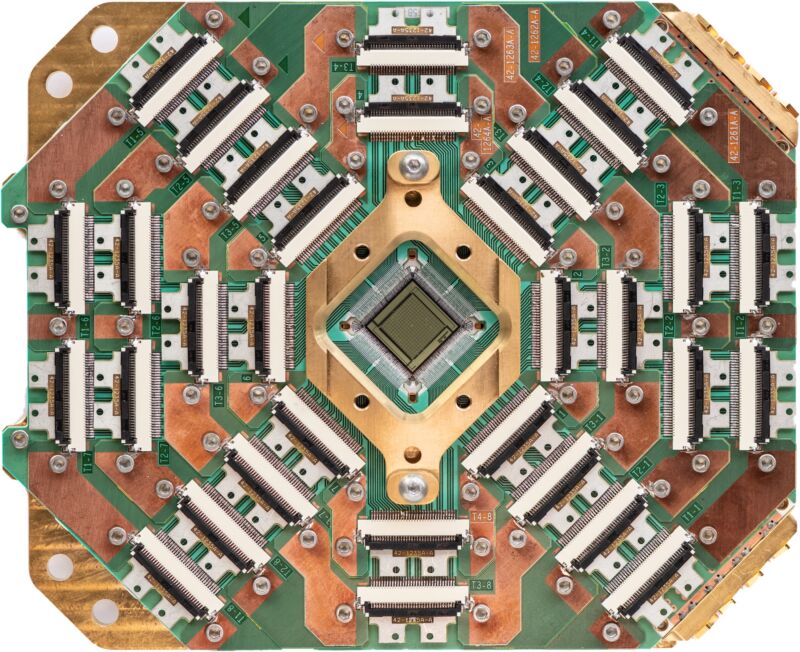 Image of a chip surrounded by complicated support hardware.