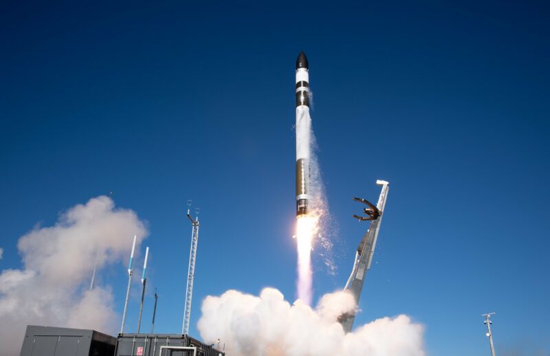 A rocket lifts off against a blue sky.