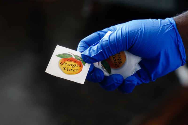 A polling-place worker holds an "I'm a Georgia Voter" sticker during the primary election on June 9, 2020 in Atlanta.