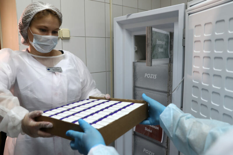 Image of a women in medical protective gear holding a box of samples.