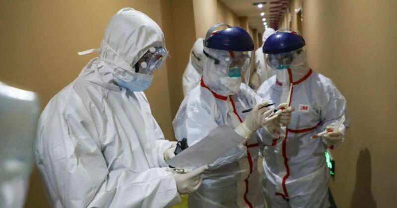 People in protective gear examine pages of notes.