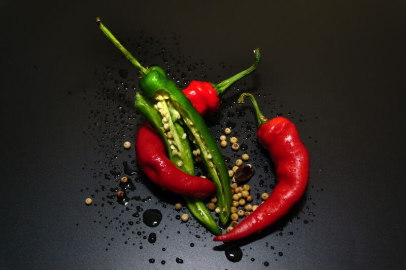 Seeds spill out of a trio of hot peppers in a skillet.