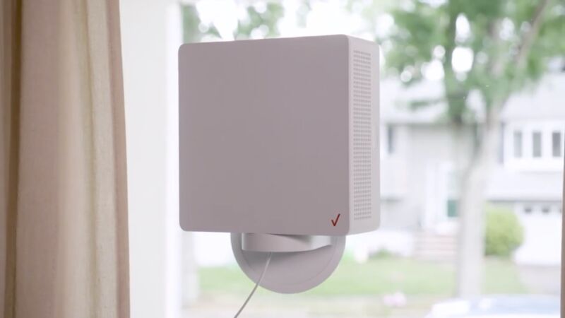 A Verizon 5G Home Internet device mounted on the inside of a window, at a home on a residential street.