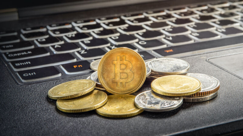 A stack of coins with the bitcoin logo sits on top of a laptop keyboard.