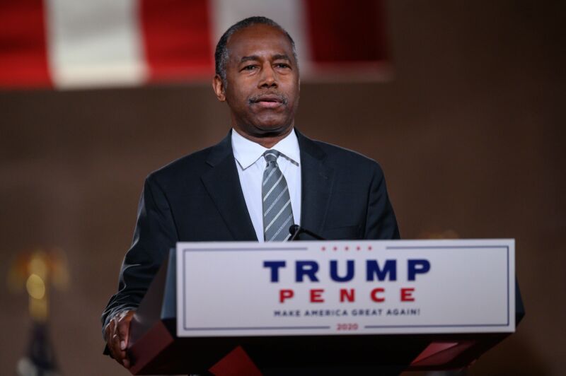 A man in a suit speaks at a podium.