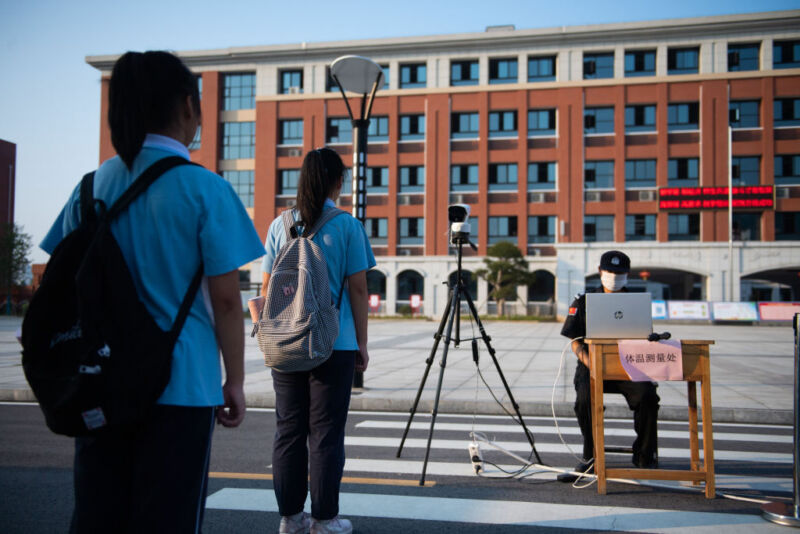 Image of children in a line in front of an official with a sensor on a tripod.