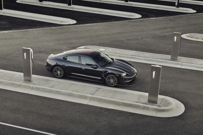 A black Porsche Taycan plugged into a sleek-looking charger