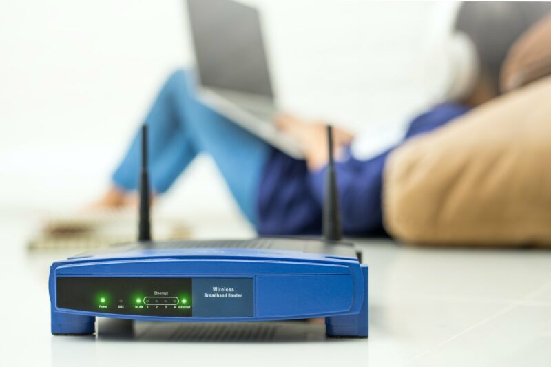 A wireless router seen near a woman using a laptop.
